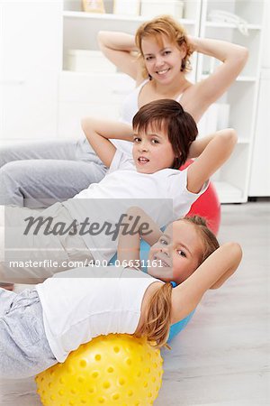 Kids with their mother doing gymnastic exercises with large balls at home