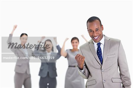 Close-up of a successful business team with man in foreground smiling and clenching his fist with three co-workers raising their arms