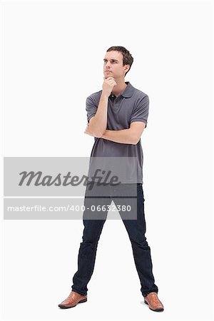 Thoughtful standing man and his legs apart looking up against white background
