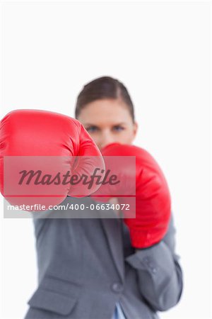 Attacking fist of tradeswoman in boxing glove against a white background