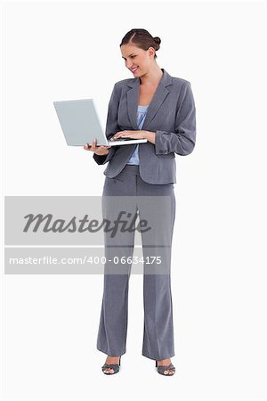 Smiling tradeswoman working on her laptop against a white background