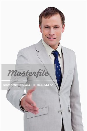 Smiling businessman offering his hand against a white background