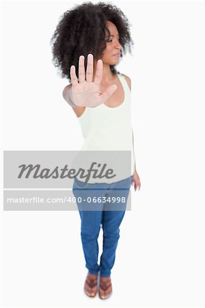 Young woman with curly hair looking on the side while showing the hand stop sign