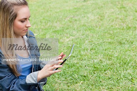 Young serious girl using her tablet computer in a public garden