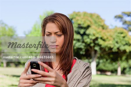 Woman curiously reading a text message in a sunny park area