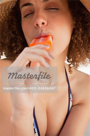 Young woman closing her eyes while eating a delicious ice lolly on the beach