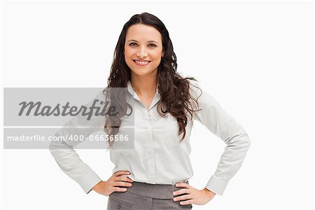 Portrait of a brunette businesswoman hands on hips smiling against a white background