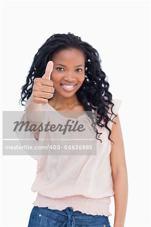 A girl is smiling and is giving a thumb up against a white background