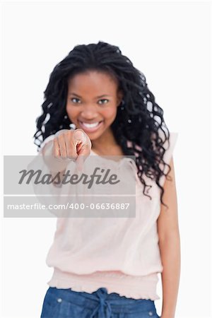 A smiling woman is pointing her finger at the camera against a white background