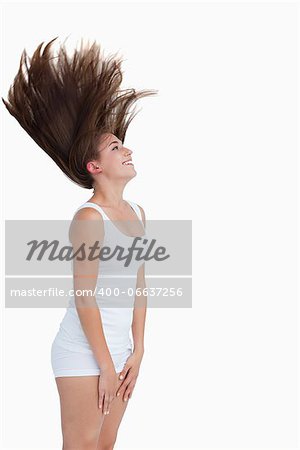 Smiling brunette flipping her hair against a white background