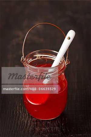 Sweet homemade barry jam in a glass jar on an old wooden background.