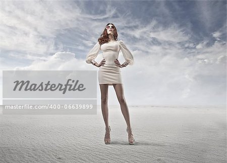 Young woman with a white dress standing in a fake desert