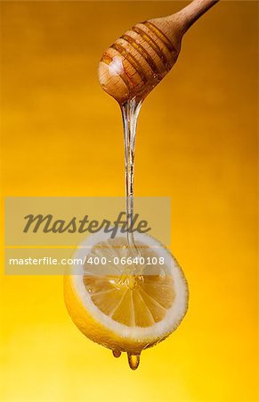 Honey flowing on lemon over yellow background