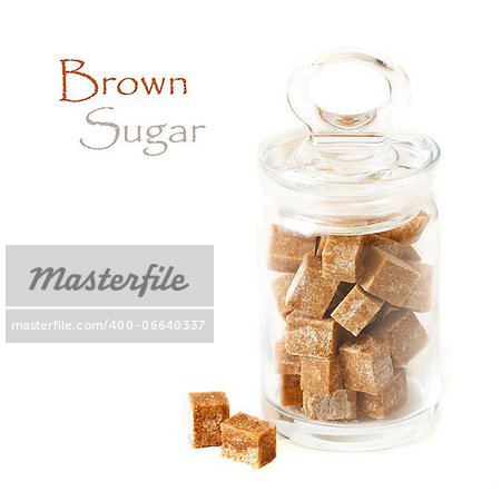 Cubes of brown  cane sugar in a glass pot on a white background.