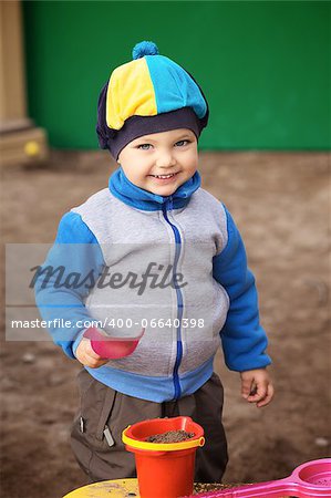 little boy playing in the sandbox at autumn