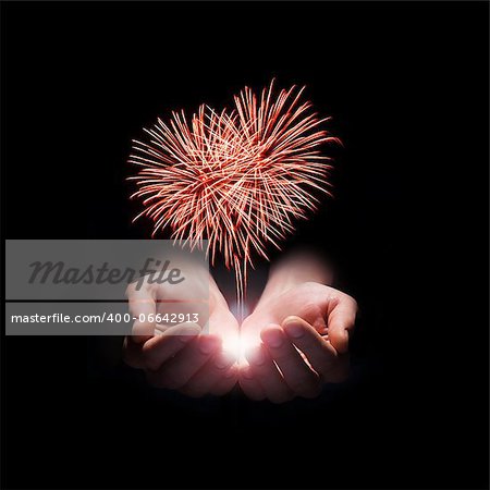 fireworks in the men's hands in the shape of a red heart on black background