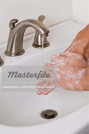 closeup of two adult hands washing with soap and running water at home