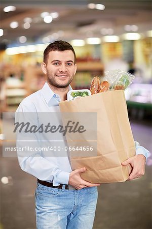 Young man with package of products in store