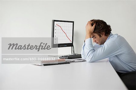 Overworked businessman with head in hands sitting at desk in office