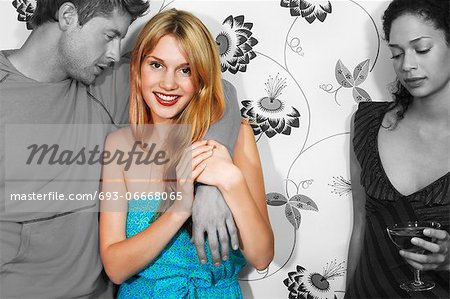 Sad young woman having drink with friends against wall