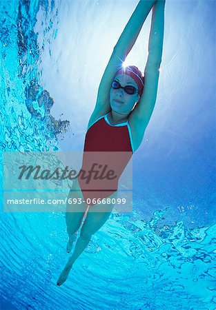 Full length of female swimmer in United States with arms raised swimsuit swimming in pool