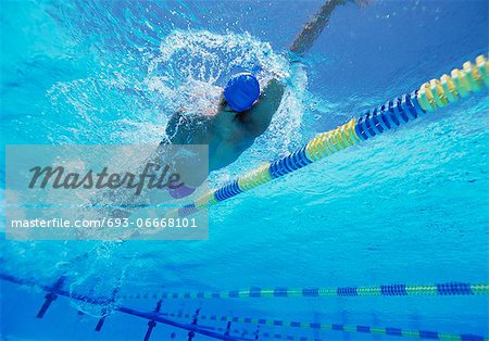 Young professional male athlete doing backstroke in swimming pool