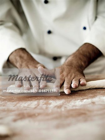 A chef rolling out gnocchi dough on a floured work surface A chef rolling out gnocchi dough on a floured work surface
