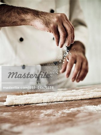 A chef dusting gnocchi dough with flour