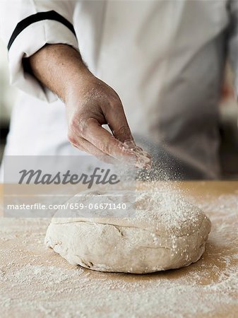 Fresh pizza dough being dusted with flour