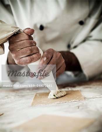 Tortellini filling being piped onto pasta dough squares Tortellini filling being piped onto pasta dough squares