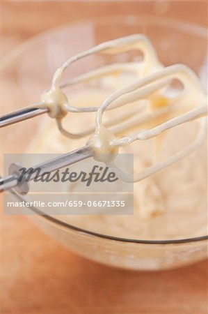Cake mixture in a glass bowl and on the whisks of the mixer