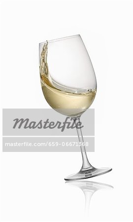 A tilting glass of white wine A tilting glass of white wine