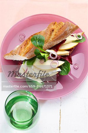 Cheese, pear slices and radicchio in a baguette, with a glass of water