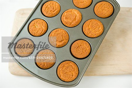 Vanilla muffins in a muffin tin on a chopping board