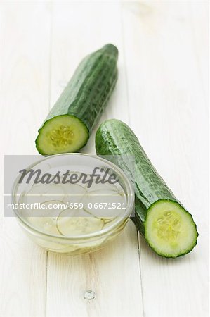 Two cucumbers and a dish of pickled cucumber slices