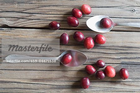 Cranberries and two spoons on a wooden surface