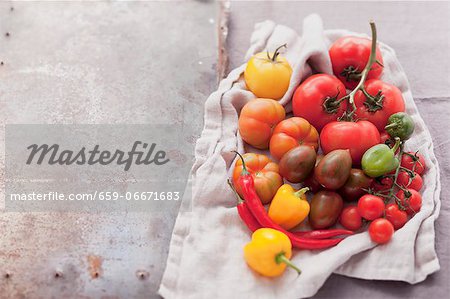 An assortment of tomatoes and chillies on a cloth An assortment of tomatoes and chillies on a cloth