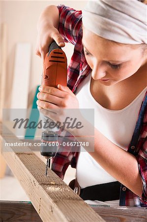 Studio Shot of Young Woman Drilling Lumber