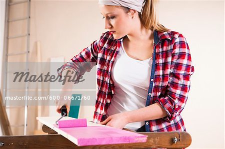 Studio Shot of Young Woman Painting Lumber