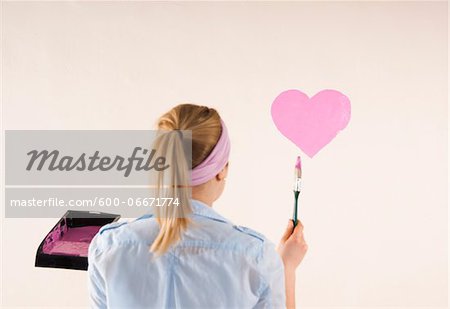 Studio Shot of Young Woman Painting Heart on Wall