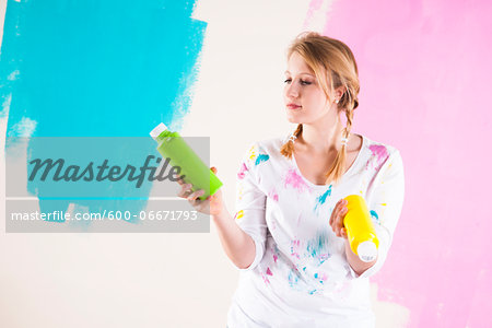 Studio Shot of Young Woman Holding Paint Containers, Deciding Between Paint Colours