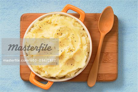 Overhead View of Dish of Mashed Potatoes on Cutting Board with Wooden Spoon