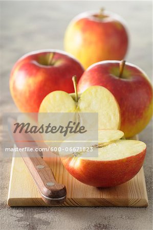 Close-up of Red Apples on Cutting Board with Knife, One Cut in Half