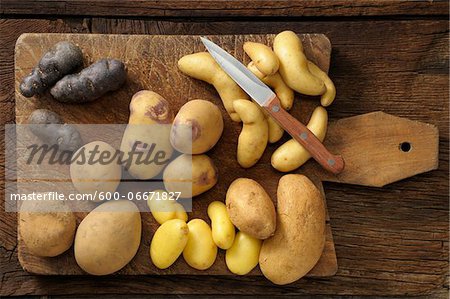 Overhead View of Varieties of Potatoes on Cutting Board with Knife Overhead View of Varieties of Potatoes on Cutting Board with Knife
