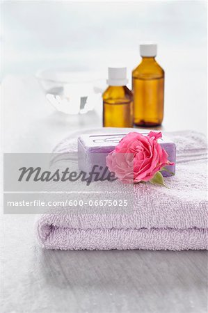 Rose and bath products like towel, soap and bottles of essential oil for aromatherapy and wellness