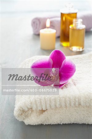 Orchid on a towel, candle, bottles of oil, wellness