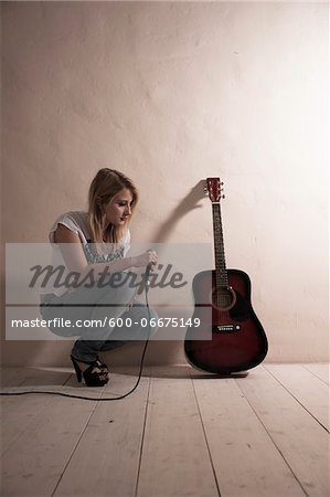 Woman Crouching with Microphone beside Guitar