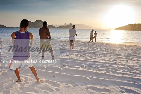 South America, Brazil, Rio de Janeiro state, Niteroi, fishermen pulling in the net on Charitas beach at sunset with Corcovado in the distance