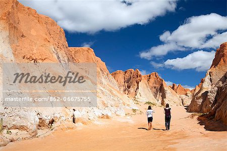 South America, Brazil, Ceara, Morro Branco, a tourist and a guide walk through a canyon in the red sandstone cliffs at Morro Branco