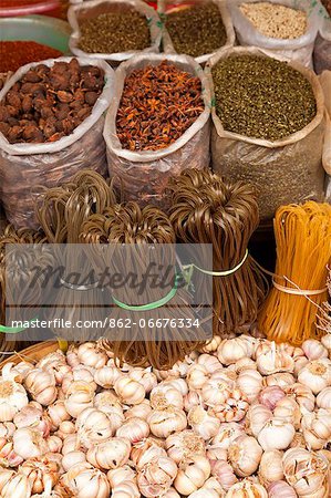 China, Yunnan, Jinghong. Spices garlic and rice noodles for sale at Jinghong market.